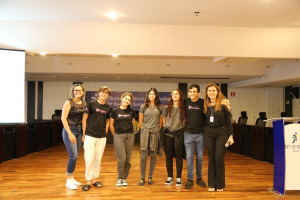 A professora, o grupo de 5 alunos e a servidora Lara posam para foto no palco do auditório Villa Boa