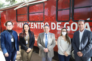 Foto colorida de três mulheres e dois homens em frente ao ônibus do Hemocentro de Goiás
