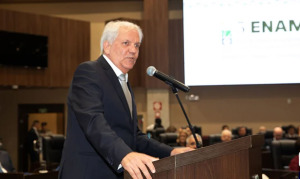 Homem de terno preto falando ao microfone