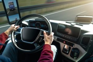 Mãos de um homem segurando o volante de um caminhão