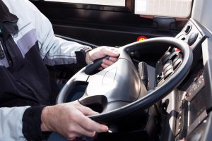 Imagem das mãos de um homem segurando o volante de um caminhão