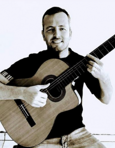 Homem de camiseta preta, segurando um violão