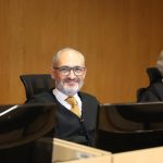Desembargador Paulo Pimenta, durante sessão plenária. Ele está sentado em frente a uma mesa com computador e microfone
