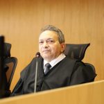 Desembargador Geraldo Rodrigues Nascimento, durante sessão plenária. Ele está sentado em frente a uma mesa com computador e microfone