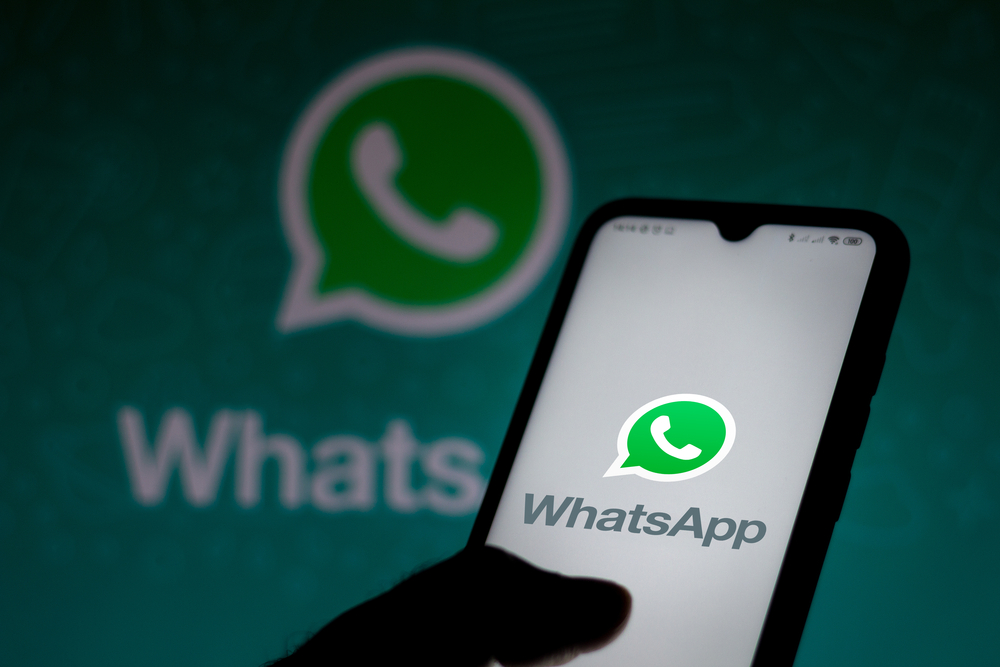 Imagem de um celular com a logotipo do whatsapp no celular e no fundo