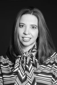 Foto de fundo preto, mulher de cabelos médios sorrindo pra foto