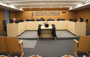 Sala de sessão de julgamento. Pessoas sentadas na bancada