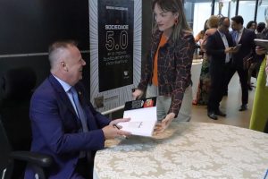 Mulher apresenta o livro para o autor autografar