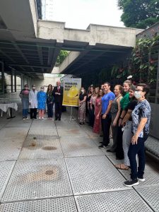 Pessoas reunidas ao redor de um banner de divulgação do Programa Trabalho Seguro.