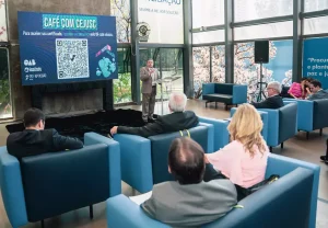 Foto da sala de espera do Cejusc com convidados sentados e o presidente do TRT  discursando ao microfone