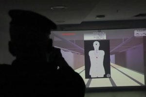 Agente de segurança aponta arma para alvo projeto na parede, por meio de simulador virtual