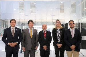 Servidores durante evento. Tratam-se de 4 homens e 1 mulher, estão todos de pé, alinhados lado a lado e posando para a foto.