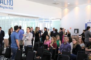 Foto de público circulando no salão durante evento.