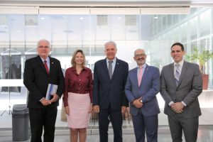 Foto de magistrados, servidores, e palestrante durante evento. Tratam-se de 4 homens e 1 mulher, estão todos de pé, alinhados lado a lado e posando para a foto.