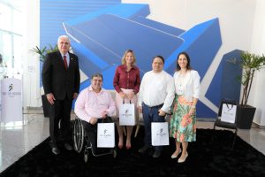 Foto dos participantes e palestrantes do evento reunidos para foto. Na foto há 2 mulheres e 2 homens de pé, e um cadeirante. Todos alinhados lado a lado posando para a foto.