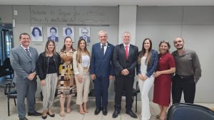 Foto do Desembargador Eugênio Cesário com a equipe da Vara do Trabalho de Luziânia. Tratam-se de 4 homens e 5 mulheres, estão todos de pé, posicionados lado a lado e posando para a foto.