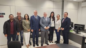 Foto do desembargador Eugênio Cesário com a equipe da Vara de Trabalho de Valparaíso de Goiás. Tratam-se de 5 homens e 3 mulheres, todos de pé, posicionados lado a lado e posando para a foto.