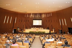 Foto de plateia durante cerimônia. Trata-se de um grupo de pessoas, sentadas nas cadeiras do auditório Goyases, de frente para o palco.