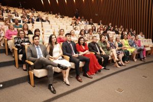 Foto de plateia durante cerimônia. Trata-se de um grupo de pessoas, sentadas nas cadeiras do auditório Goyases, de frente para o palco.