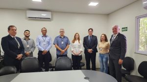 Foto do Corregedor-regional, desembargador Eugênio Cesário, com a equipe da Vara de Trabalho de São Luís de Montes Belos. Tratam-se de 6 homens e 2 mulheres, estão todos de pé, lado a lado, atrás de uma mesa, posando para a foto.