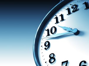 Imagem com fundo azul mostrando um relógio de ponteiros em primeiro plano