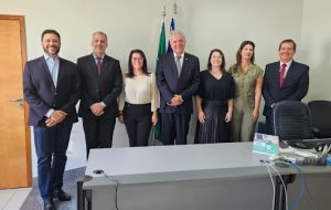Advogadas e membros do TRT de Goiás em pé, em posição para foto, atrás de uma mesa.