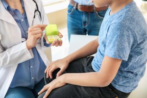Menino é atendido por médica e está acompanhado de um adulto.