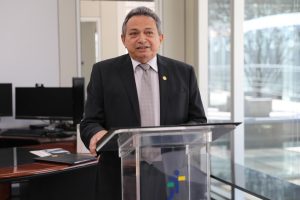 Foto colorida do presidente do TRT discursando. Trata-se de um homem branco, de cabelo curto, liso e grisalho. O magistrado veste um terno preto e fala atrás de um púlpito.