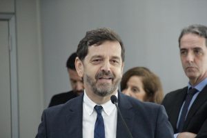 Foto colorida do juiz Luciano Crispim. Trata-se de um homem branco, de cabelos curtos, lisos e castanhos. Ele usa terno e está falando ao microfone.