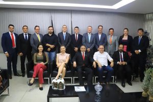 Foto mostra representantes da advocacia de Anápolis, homens e mulheres, com o presidente do TRT-18 e servidores. A maioria está em pé, lado a lado, atrás, enquanto outros estão sentados, à frente