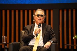 Foto do desembargador Ricardo Tadeu sentado com o microfone na mão