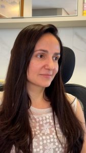 Mulher branca de cabelos pretos compridos e lisos, vestindo uma blusa branca