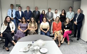 Algumas pessoas em pé e outras sentadas na frente. No rodapé, a logo da Justiça do Trabalho