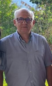 Homem vestindo camisa cinza claro, usando óculos, em pé
