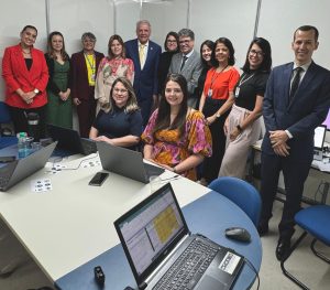 Grupo de 11 pessoas em pé e 2 pessoas sentadas em uma sala de audiências no Centro de Convenções