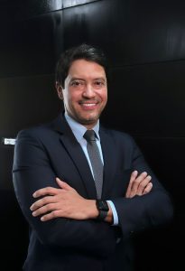 Foto do juiz Cleber Sales. Ele está vestido de terno preto, está com os braços cruzados e sorri para a foto