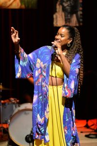 Foto da cantora Larissa Ribeiro cantando no palco.