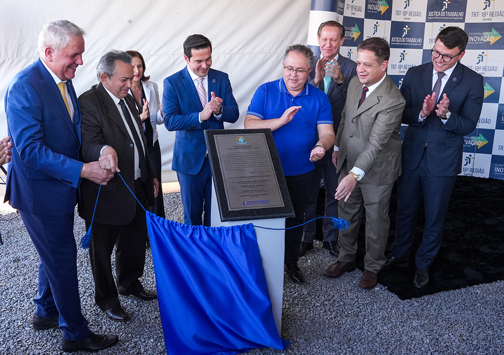 Na imagem, há um grupo de nove homens em pé, na inauguração da Pedra Fundamental das futuras instalações do Foro Trabalhista de Anápolis. No centro, está a placa de inauguração em destaque. O homem à esque