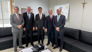 Cinco homens vestindo trajes formais estão em pé, lado a lado