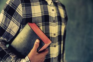 imagem mostra parcialmente um homem segurando uma bíblia.