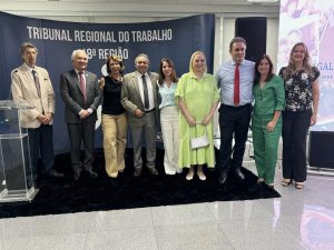 Várias pessoas em pé e atrás o nome do Tribunal Regional do Trabalho da 18ª R