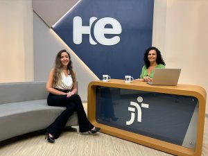 
Uma mulher sentada em uma poltrona e um mulher numa bancada. Elas olham para a câmara. Ao fundo, a logomarca do programa hora extra. Embaixo da bancada, a logomarca da Justiça do Trabalho
