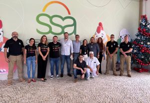 Várias pessoas posando para foto com a logo da empresa SSA na parede atrás