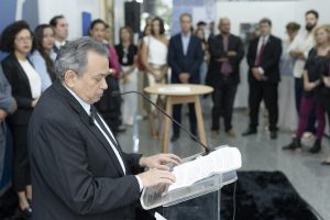 Homem discursa em púlpito e no fundo há plateia