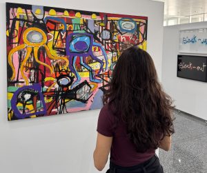 Mulher em frente a uma pintura abstrata colorida