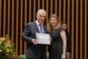 Homem e mulher em trajes formais segurando um certificado
