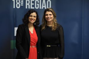 duas mulheres sorrindo para a foto usando trajes formais