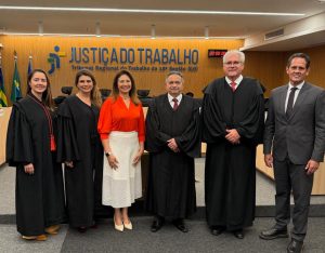 Seis pessoas em pé posando para foto em um ambiente fechado.