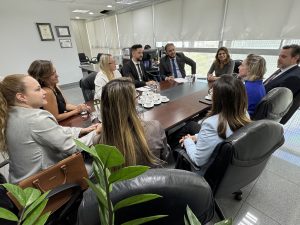 Um grupo de pessoas vestidas formalmente sentadas em volta de uma mesa conversando.