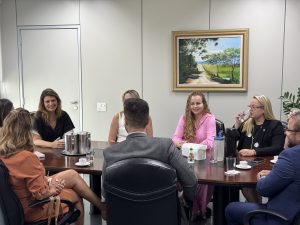 Um grupo de pessoas vestidas formalmente sentadas em volta de uma mesa conversando.